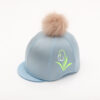 The Snowdrop Riding Hat Cover is a very delicate design in soft white glitter and fresh apple green on a pretty light blue silk topped with a fluffy pom